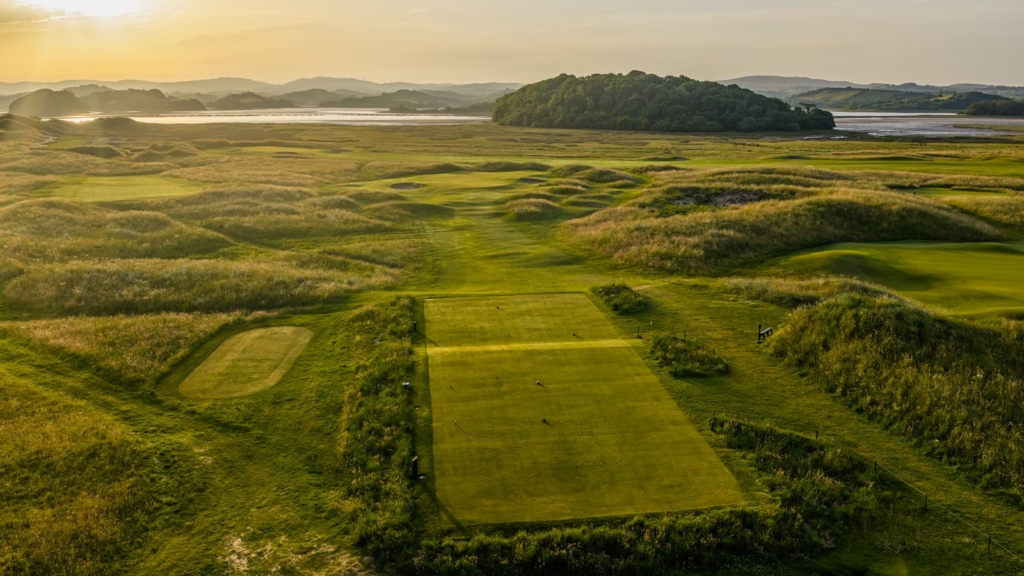 a fairway surrounded by green dunes at sunset