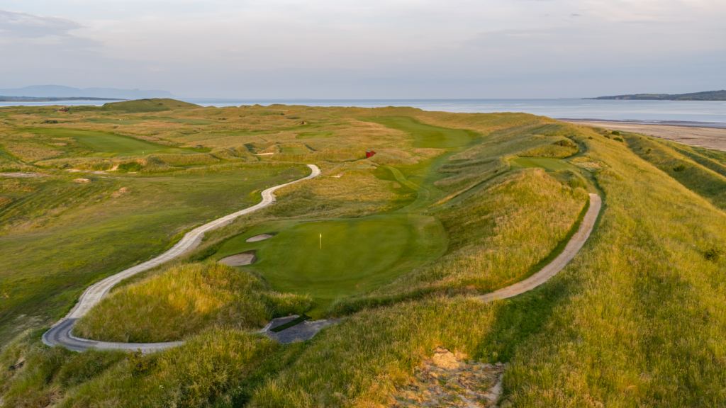 a stone path winding through the golf course featuring green hills and small sand pits