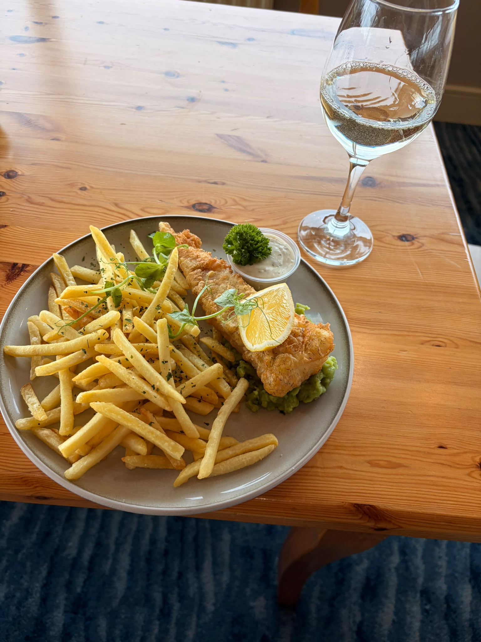 breaded fish and chips with mushy peas and a glass of white wine